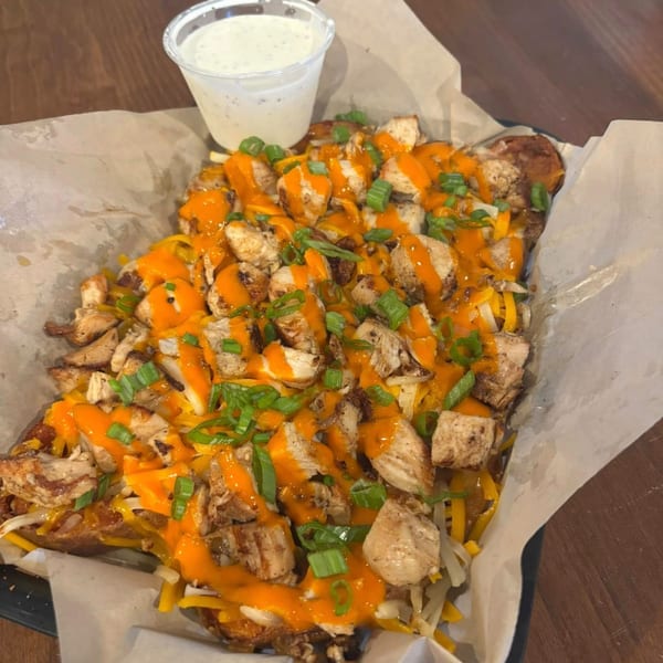 TJ's loaded fries topped with chicken, cheese, orange sauce, and green onions, with a side of ranch.