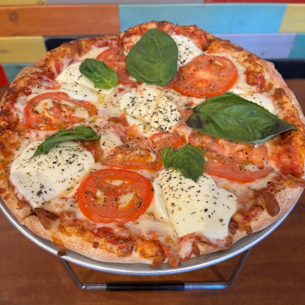 A TJ's Burgers, Wings, and Pizza Margherita pizza with fresh basil, mozzarella, and sliced tomatoes.